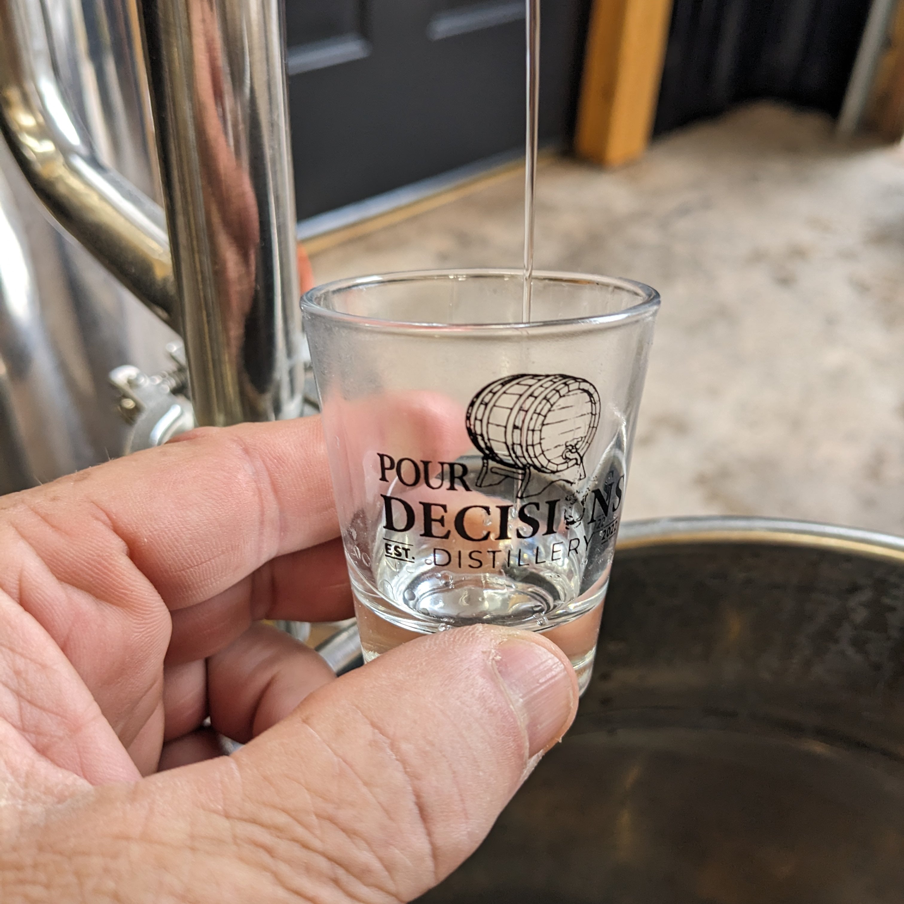 Pour Decisions Distillery shot glass with whiskey dripping from still